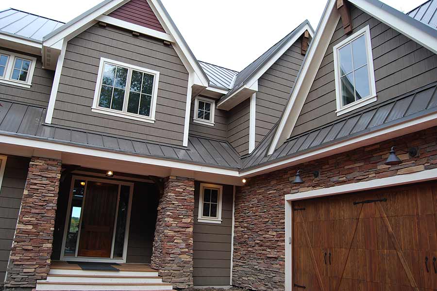 Brown two story home with stone accents and nice wood front door.