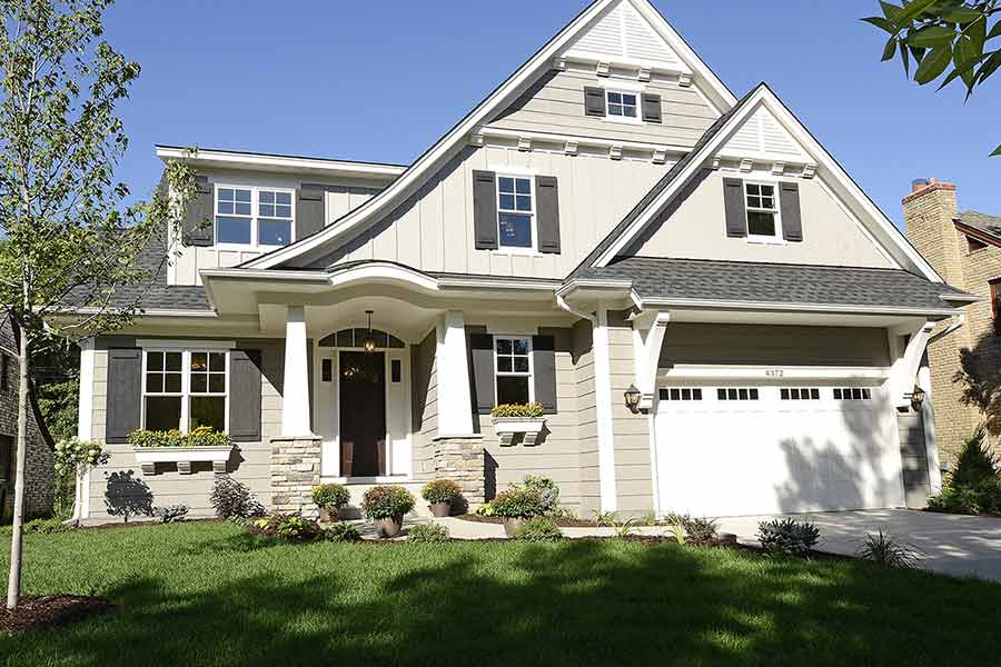 Light tan or gray two story home with stone trim and two car garage.