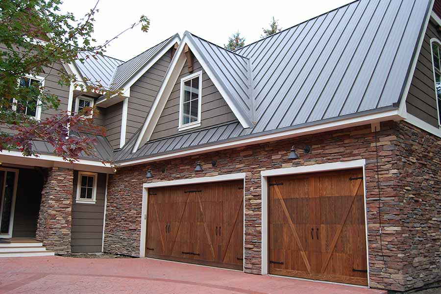 Large three car stone garage with steel roofing.