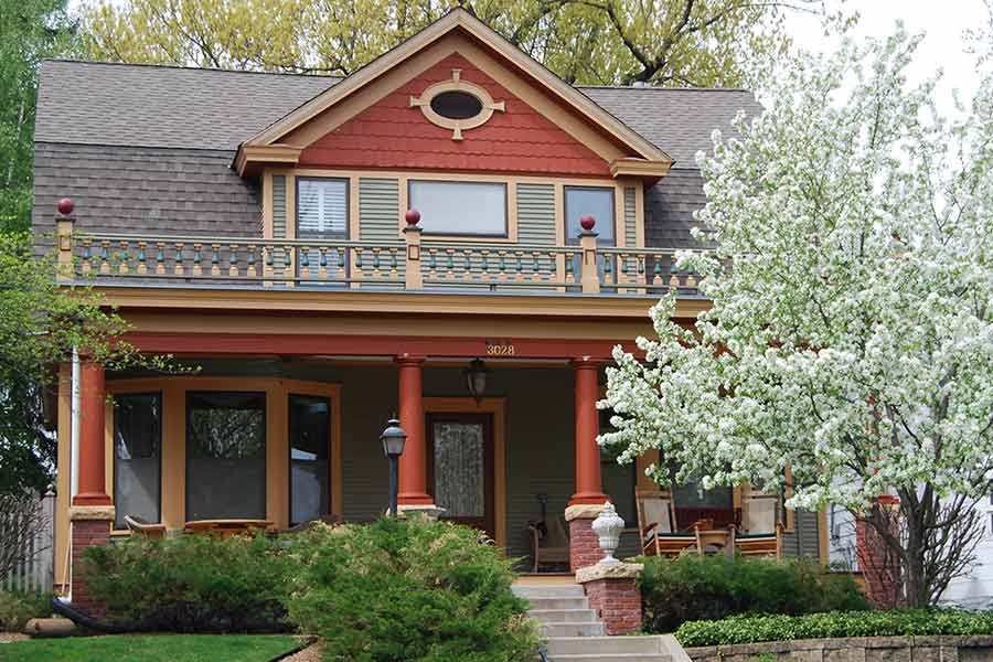 Red two story home with nice second story porch and nice cherry blossom tree in front yard.