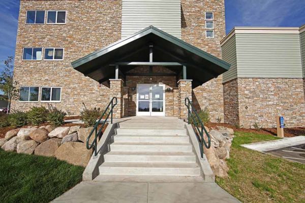 Entryway to an all stone three story commercial building with nice boulder landscaping.