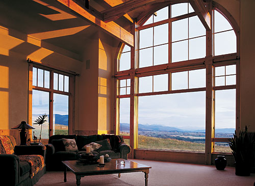 Inside a huge living room with high ceiling and massive custom window with a view.