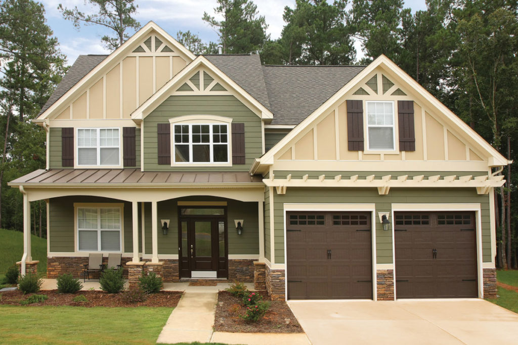 Light green and cream two story home with stone accents and two car garage.