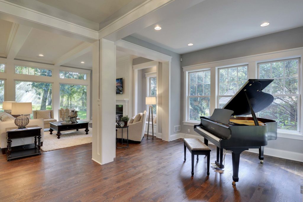 Inside home's living room with grand piano and lots of windows.