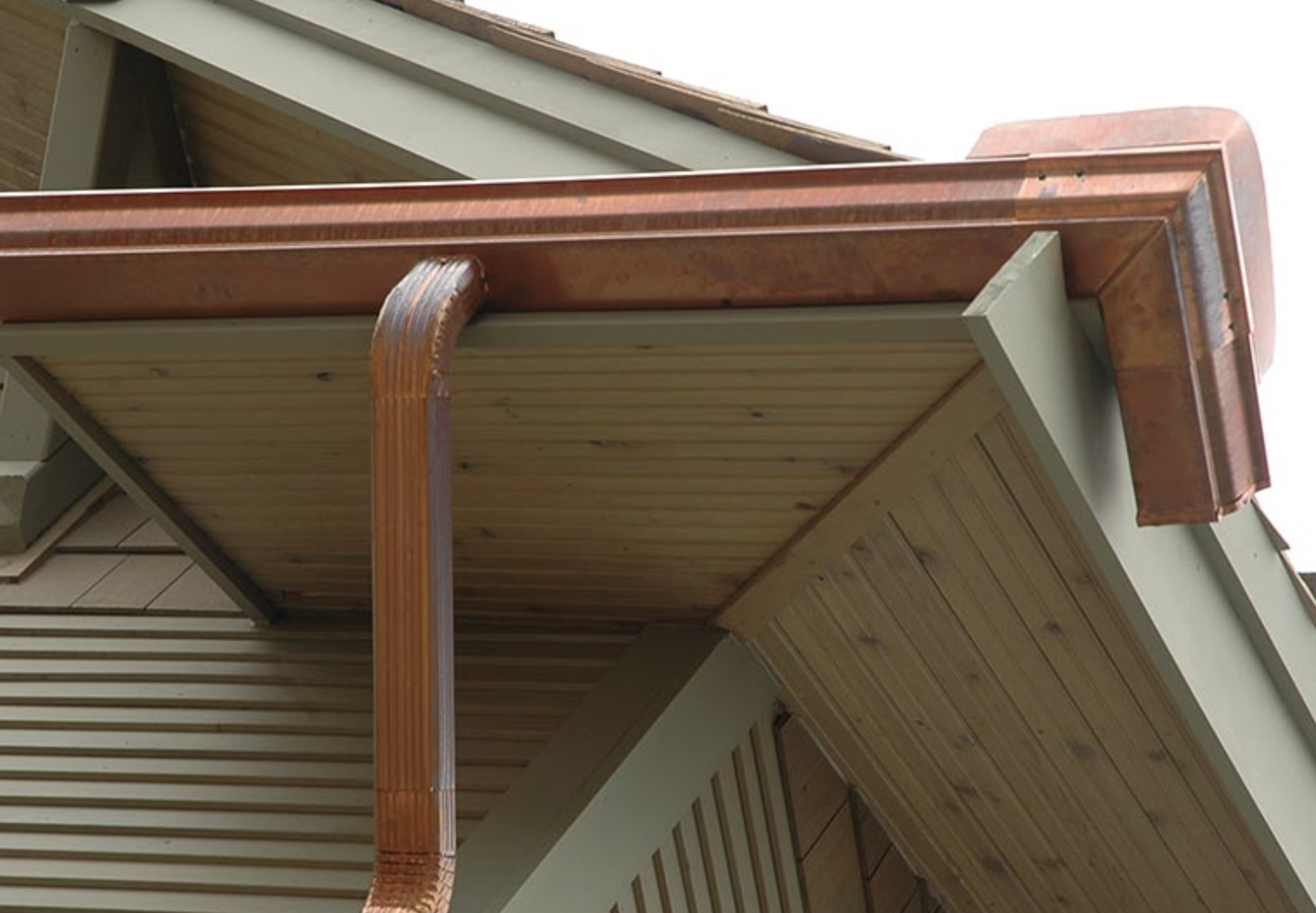 copper gutter and downspout on the corner of a home's roof.