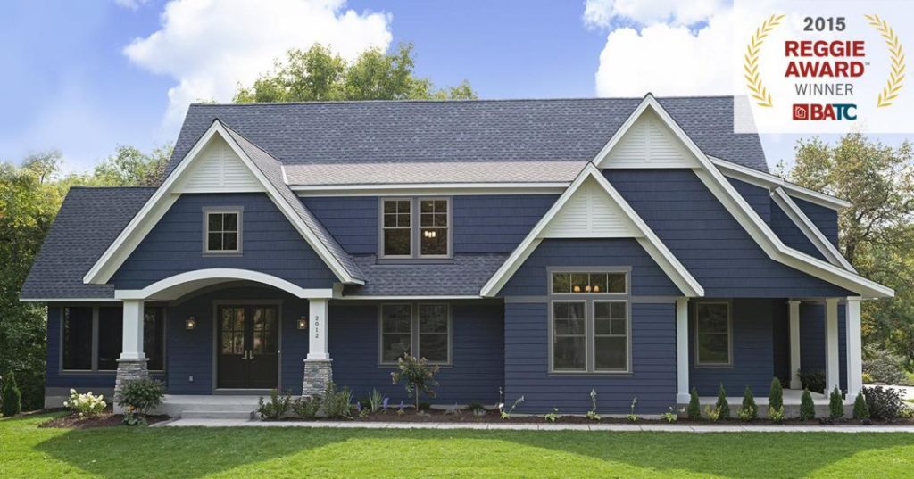 2015 Reggie Award winning blue farmhouse style home with large front door entryway and big yard.