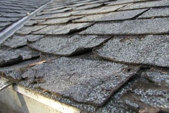 Close up of damaged roof shingles on home