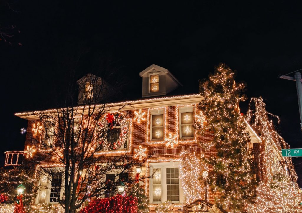 Three story brick home at night covered in christmas lights.