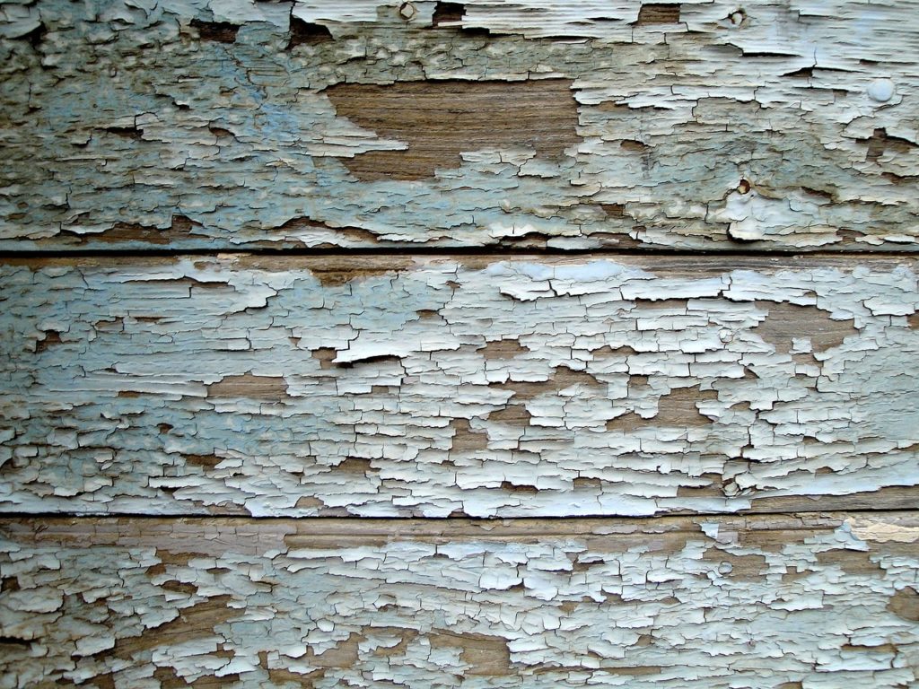 Close up example of paint chipping away off wood siding.