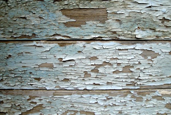 Close up example of paint chipping away off wood siding.