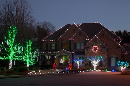 Big two story home at night and covered in christmas lights.