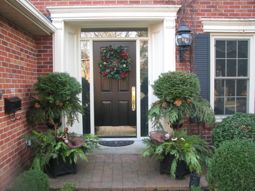 Front door of brick home with small shrubs on each side.