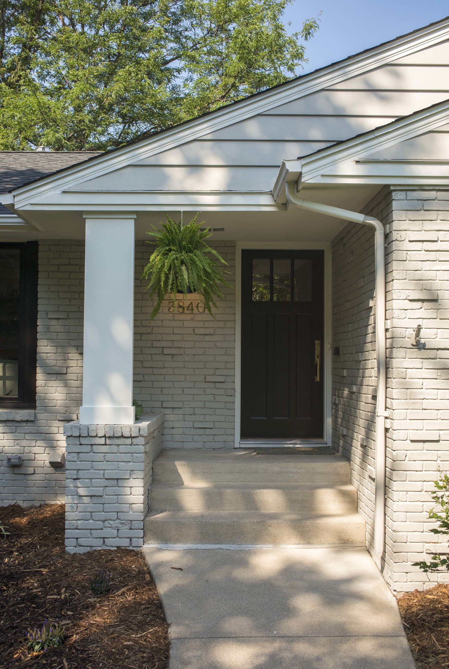 Light gray, brick home front door with planter hanging.