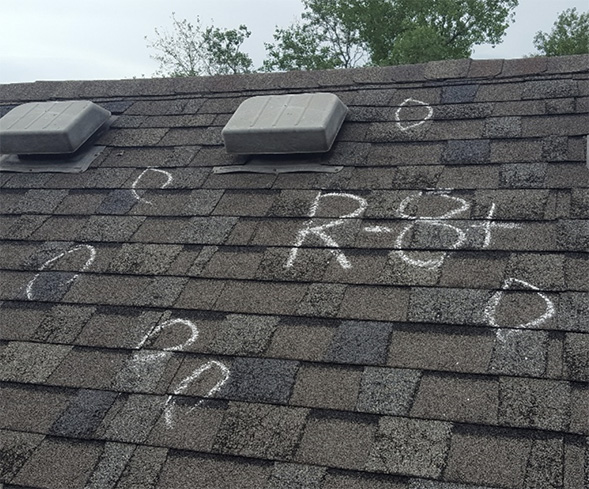Eight hail damage hits on a shingled roof marked with chalk circles and the text "R-8+" written.
