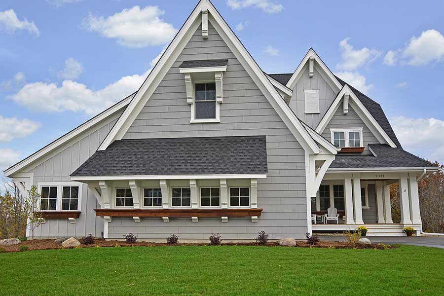 Gray two story home with very steep roof and many gables.