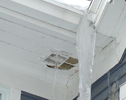 Close up of roof with damage to the downspout and gutter caused by an ice dam.