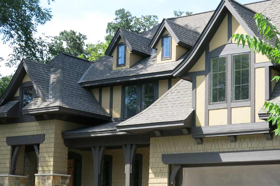 Tudor-style home siding remodel using hand-split cedar shakes and stucco panels, trim pieces and fascia.
