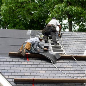Two men on roof installing shingles.