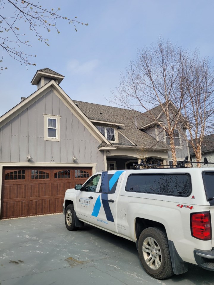 A white truck parked in front of a house, indicating roofing repair and installation services in the Twin Cities.