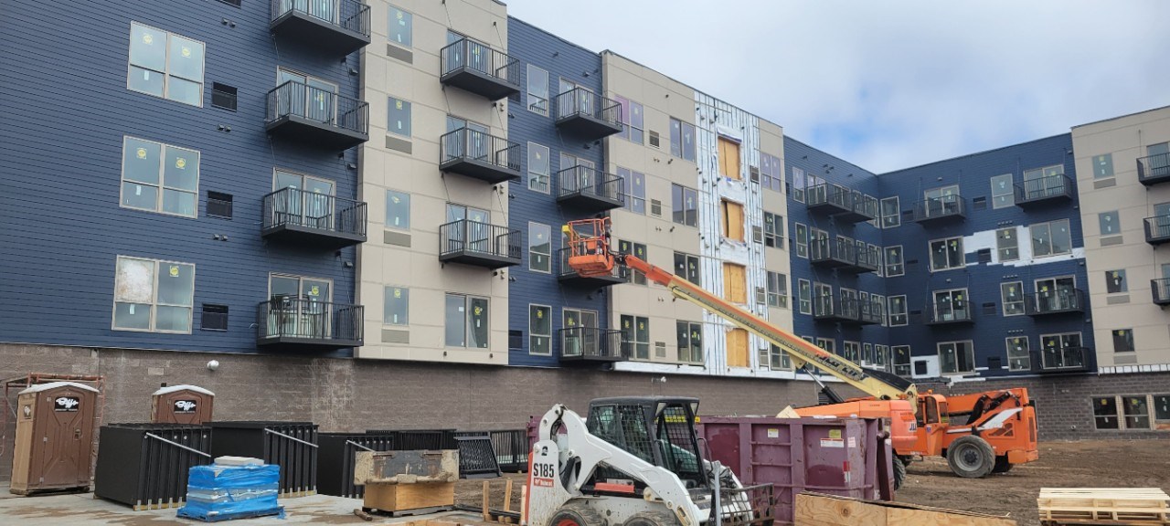 An Exteriors by Highmark worker in a lift installing a balcony on apartment building in Shakopee, MN.
