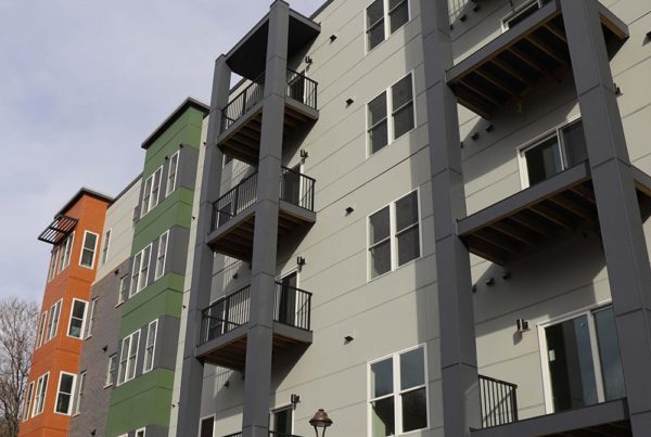 An apartment building with balconies featuring James Hardie and Nichiha siding commercial exteriors.