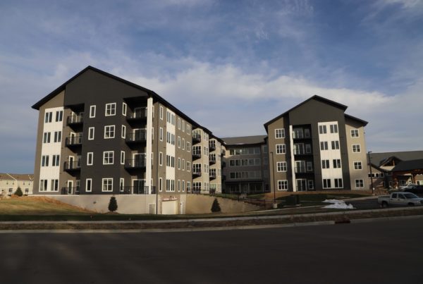 A four story multi colored apartment building with underground parking garage in Shakopee, MN.