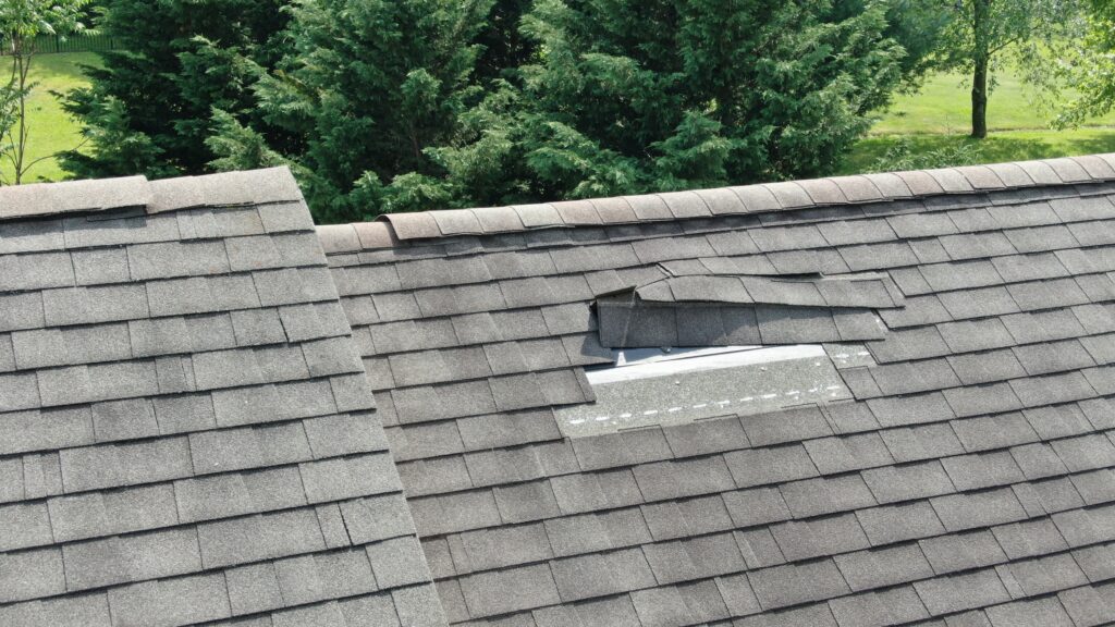 Brown shingles damaged by a storm on a residential roof