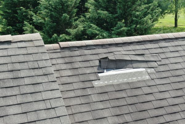 Brown shingles damaged by a storm on a residential roof