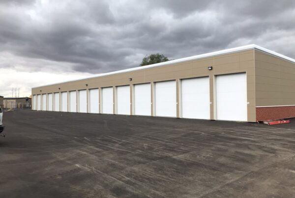 Self storage units in a parking lot with a cloudy sky.