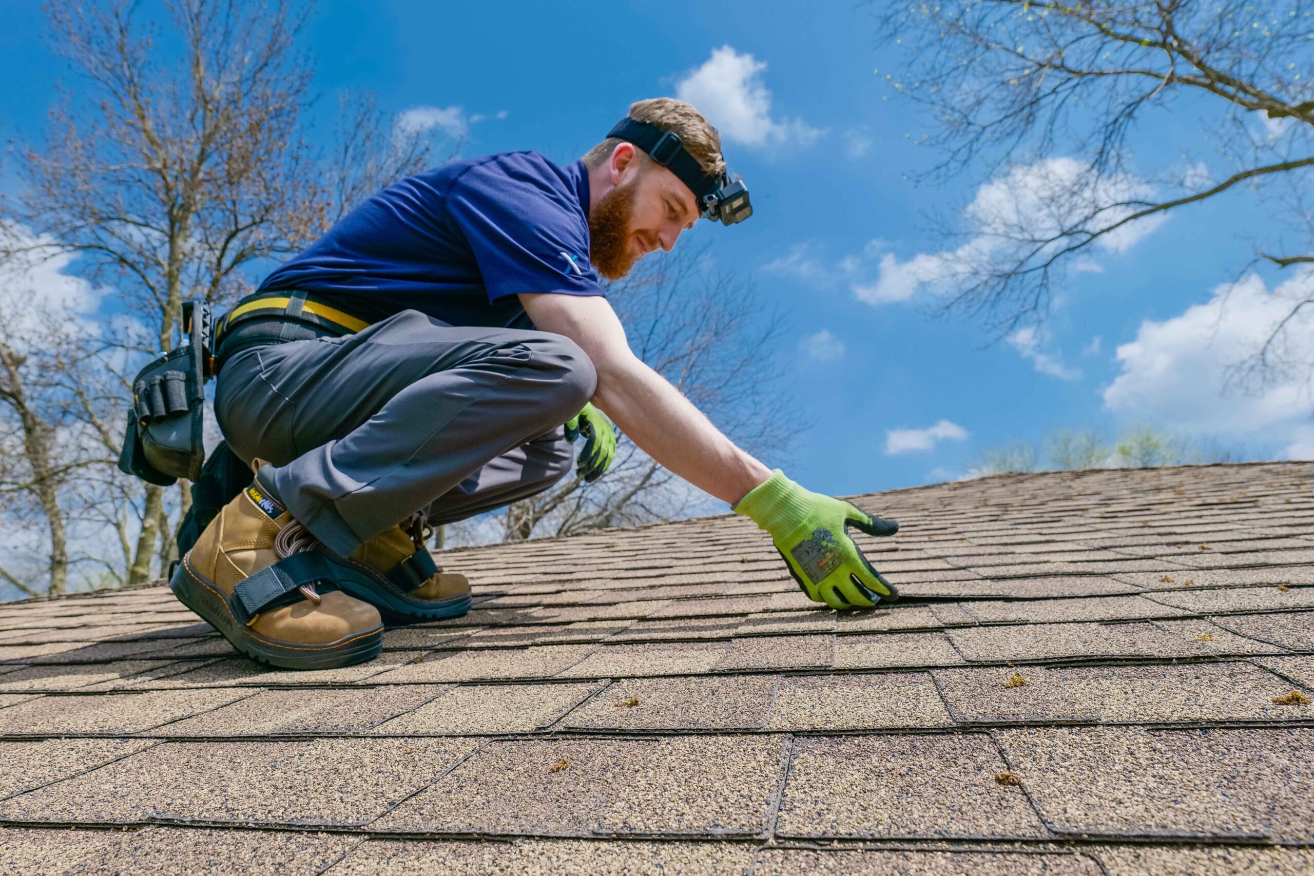 A roofer performing a shingle inspection on a roof.