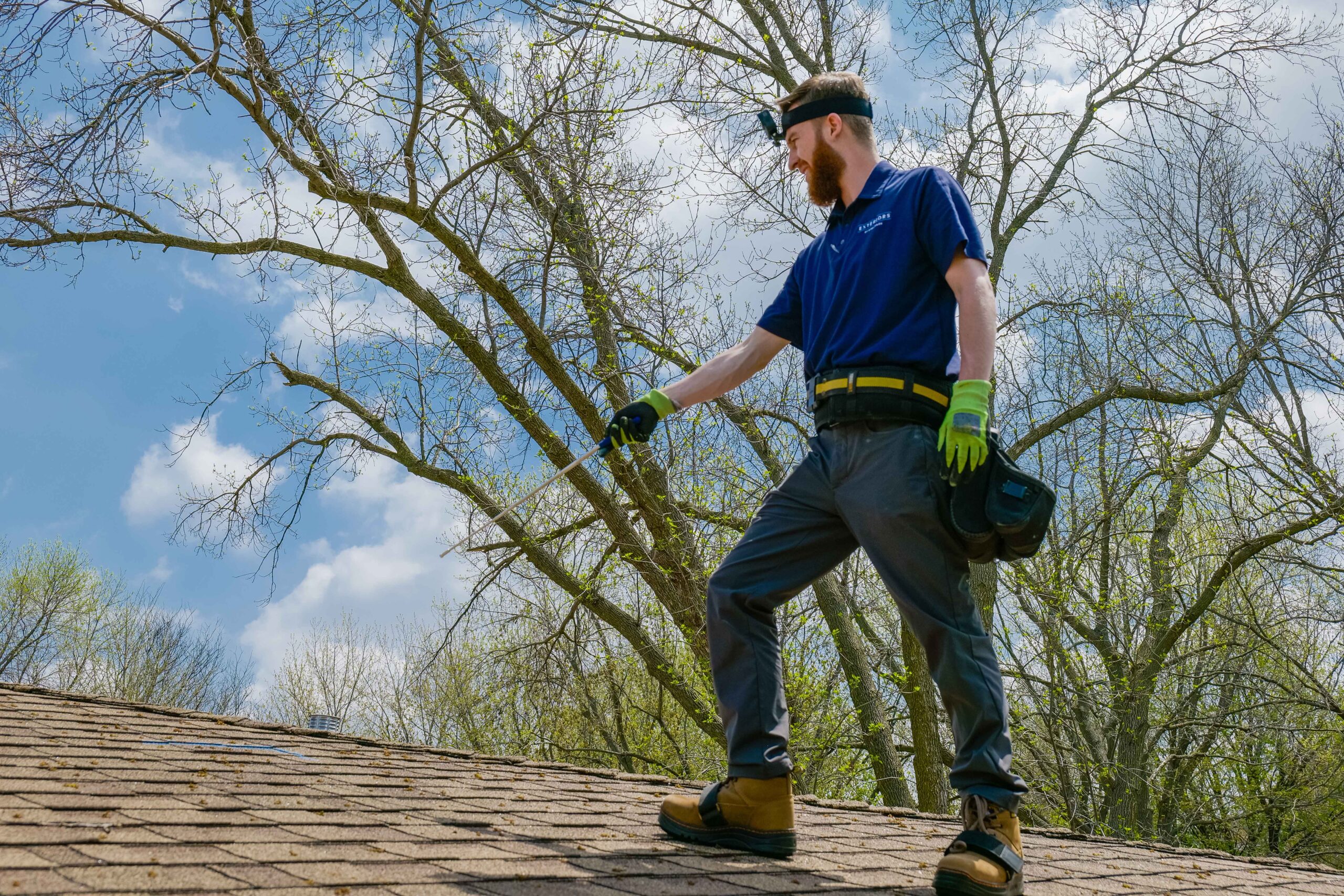 A man standing on top of a storm-damaged roof, assessing repair needs.