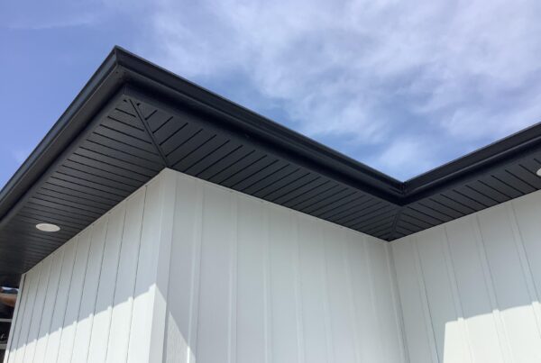 The roof of a building with white siding and black trim.